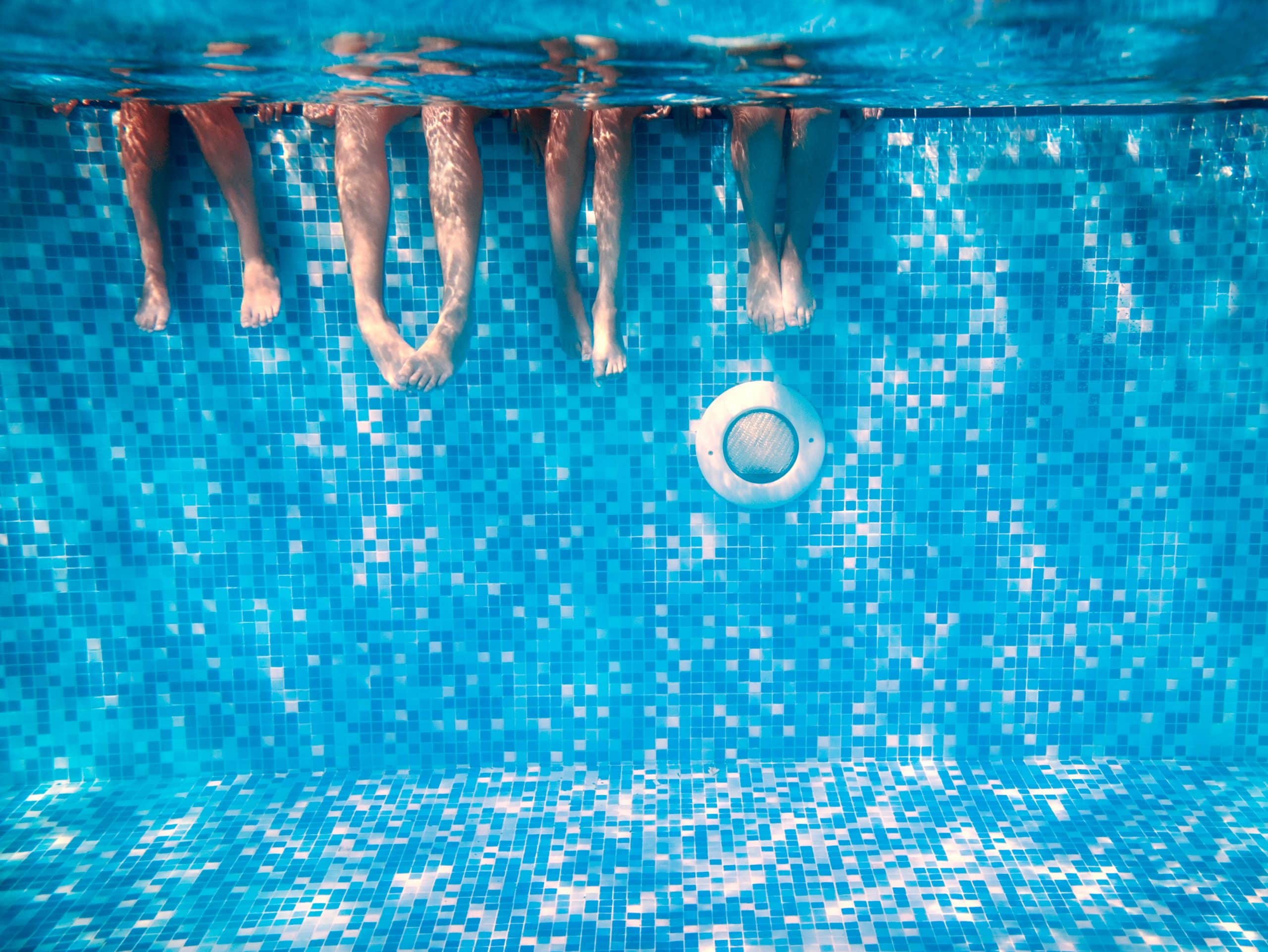 Pieds dans l'eau au dessus d'un spot d'une piscine carrelée