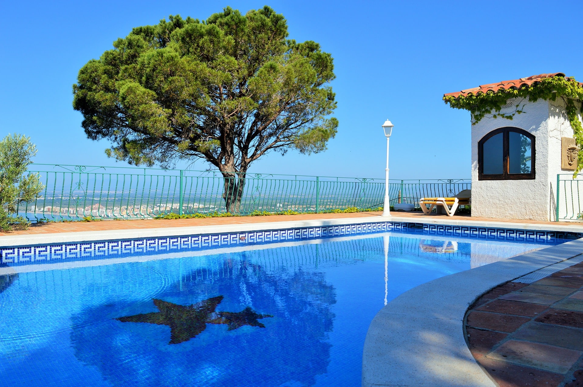 Piscine carrelée sur les hauteurs d'une côte avec un pin au milieu