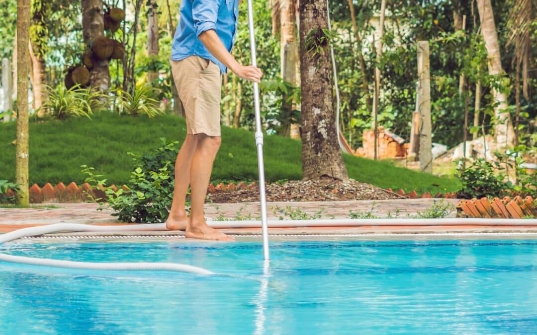 Homme passant le balais aspirant dans sa piscine