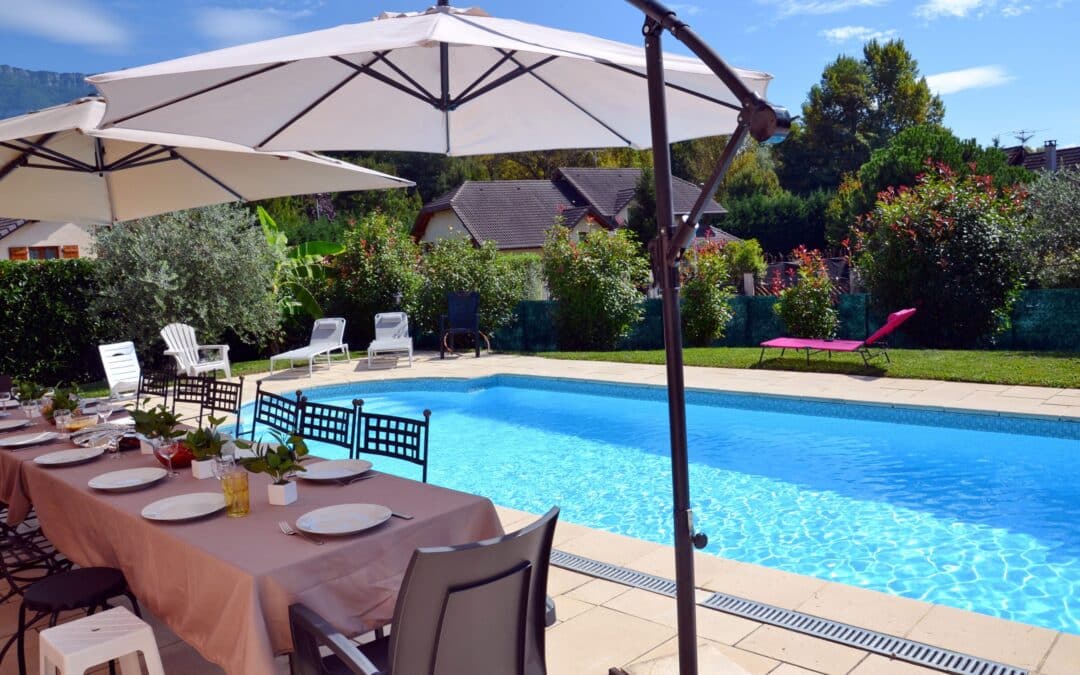 Table pour convives sous parasols devant piscine