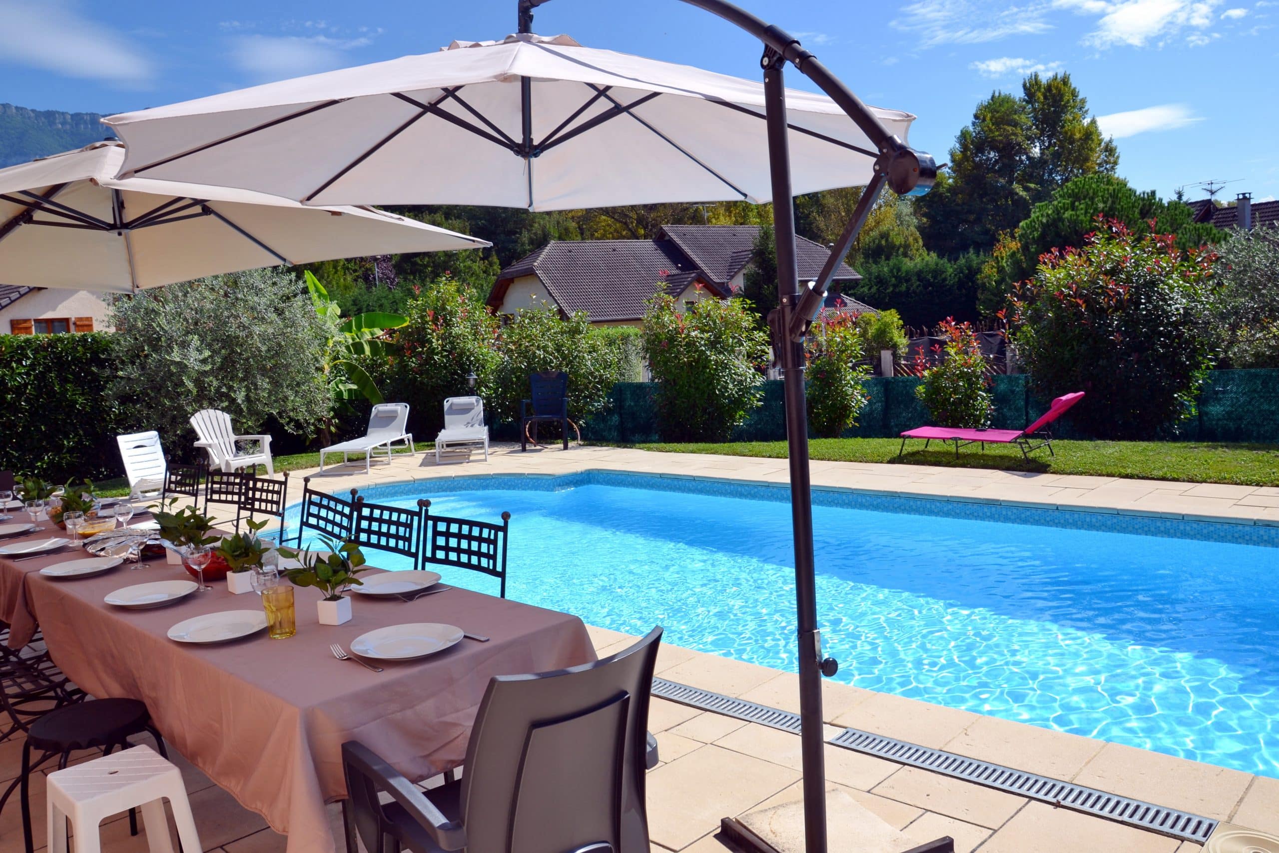 Table pour convives sous parasols devant piscine