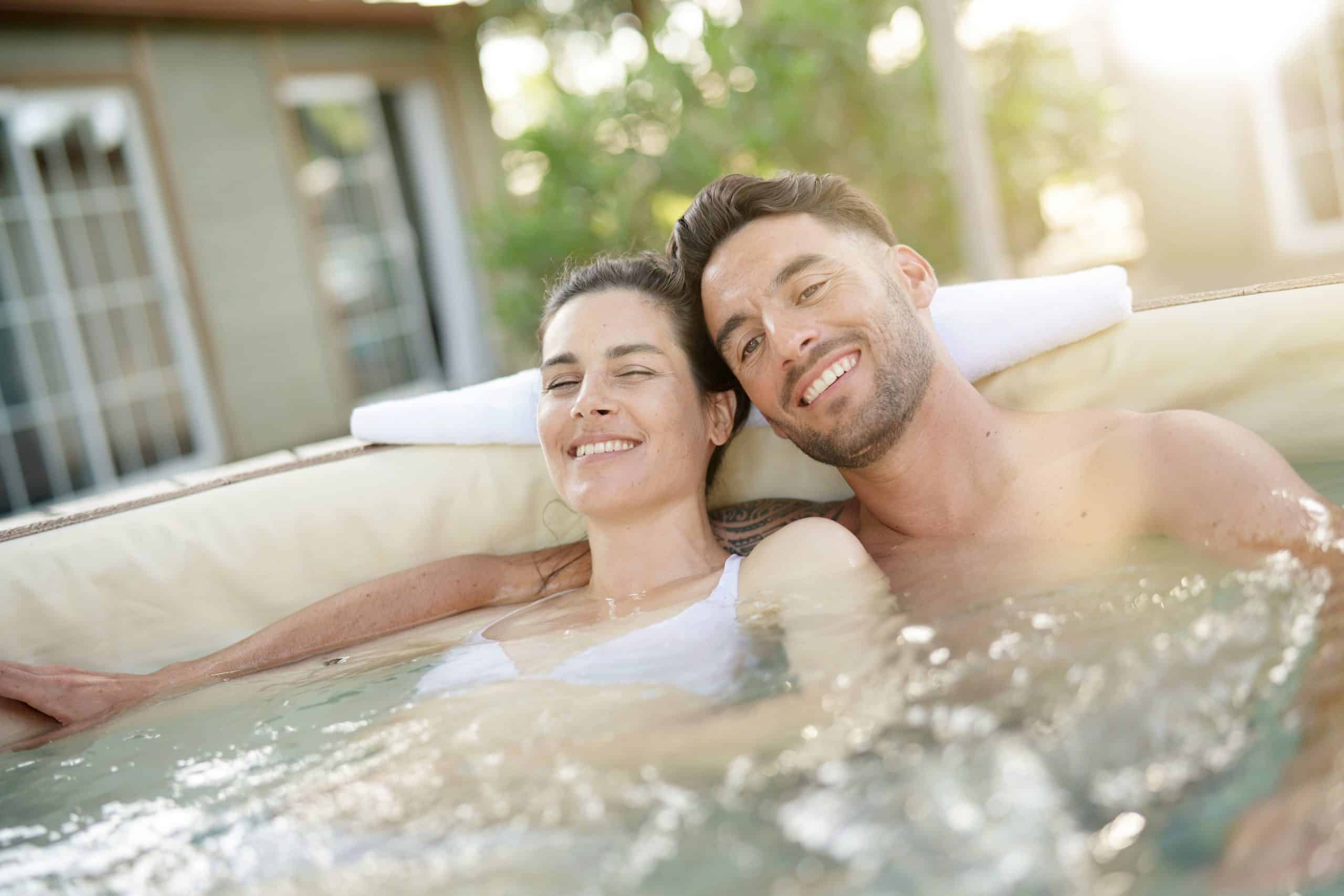 Couple jeune et souriant dans un jacuzzi