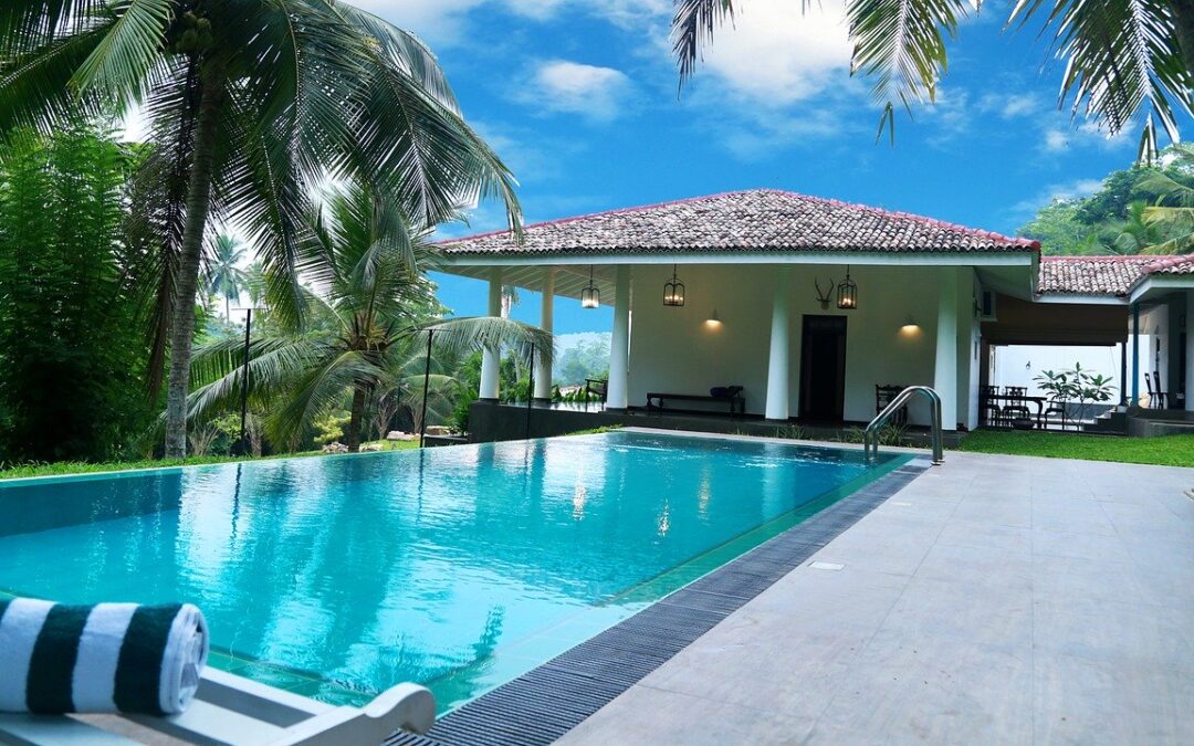 Piscine devant maison blanche à piliers entourée de cocotiers