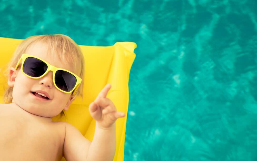 Bébé avec lunettes jaunes sur un matelas dans piscine