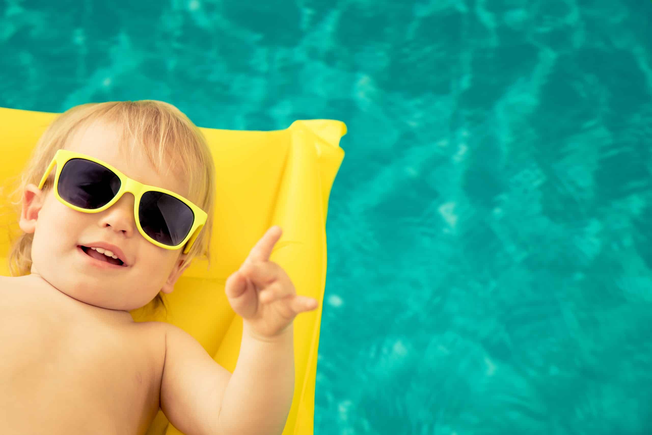 Bébé avec lunettes jaunes sur un matelas dans piscine