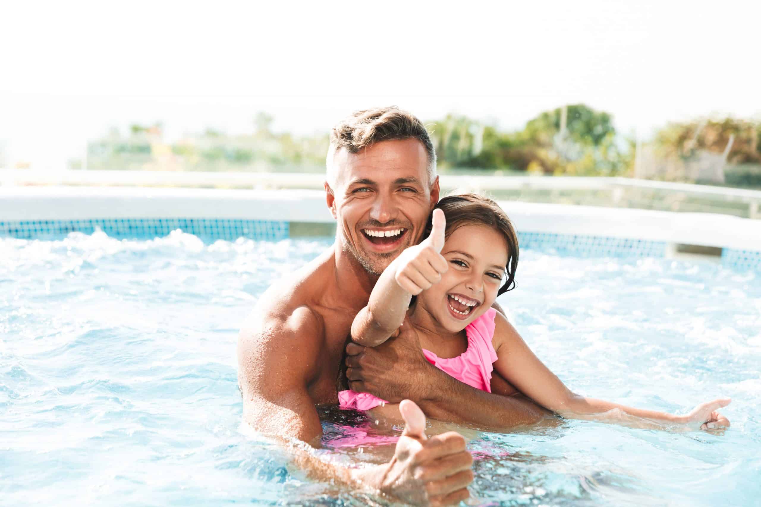 Homme et sa fille le pouce levé dans une piscine