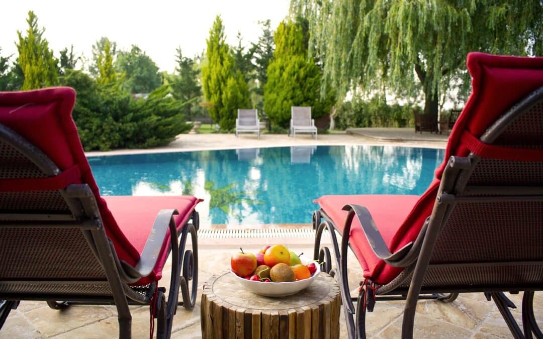 Deux fauteuils rouges en bord de piscine avec des fruits