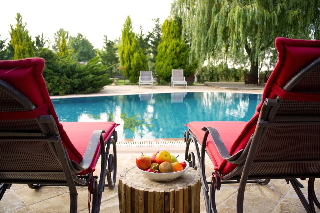 Deux fauteuils rouges en bord de piscine avec des fruits